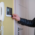 The man disarms the security alarm at the entrance to the house.